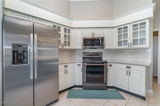 kitchen featuring white cabinets, stainless steel appliances, and light tile patterned floors