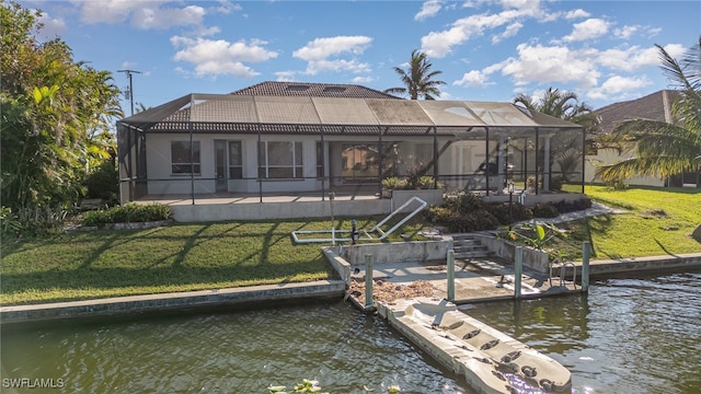 back of property with a water view, a lanai, and a lawn