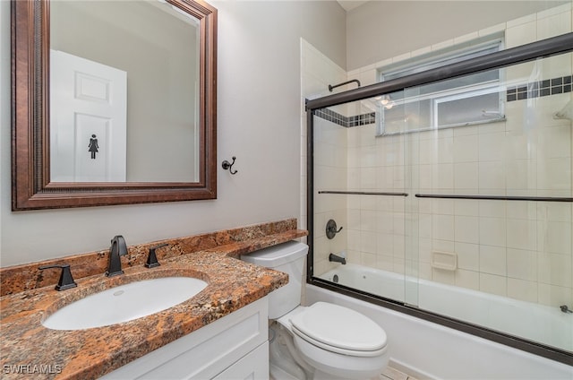 full bathroom with vanity, bath / shower combo with glass door, and toilet