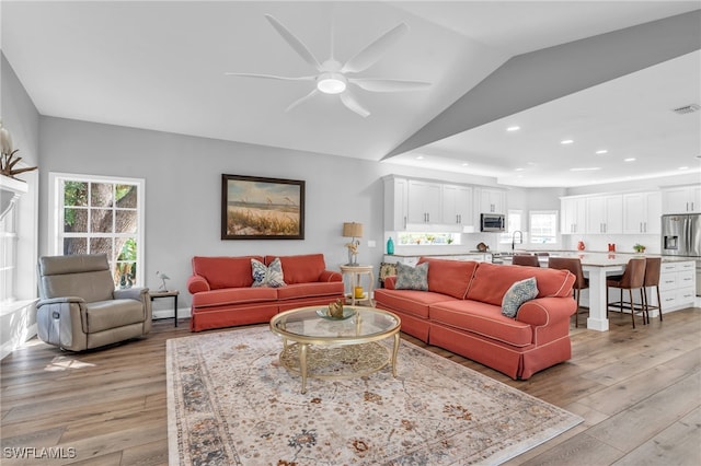 living room featuring lofted ceiling, sink, light hardwood / wood-style floors, and ceiling fan