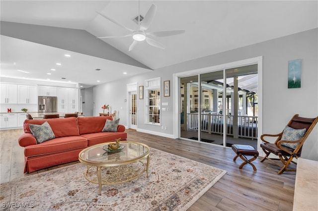 living room with light hardwood / wood-style flooring, vaulted ceiling, and ceiling fan