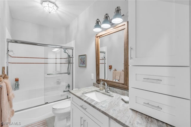 full bathroom featuring bath / shower combo with glass door, vanity, and toilet