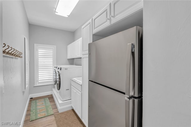 clothes washing area featuring light hardwood / wood-style floors, cabinets, and independent washer and dryer