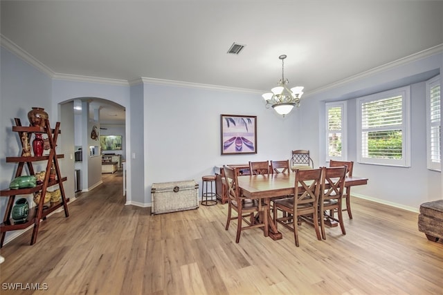 dining area with crown molding, a notable chandelier, and light hardwood / wood-style flooring