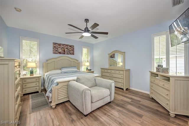 bedroom with ceiling fan, multiple windows, and hardwood / wood-style floors