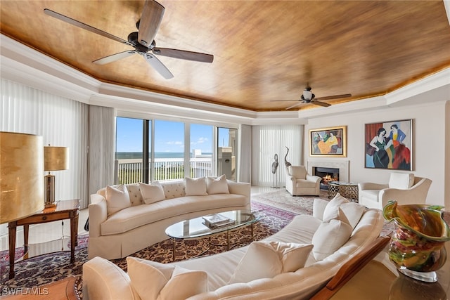 living room featuring ceiling fan, wood ceiling, ornamental molding, and a tray ceiling