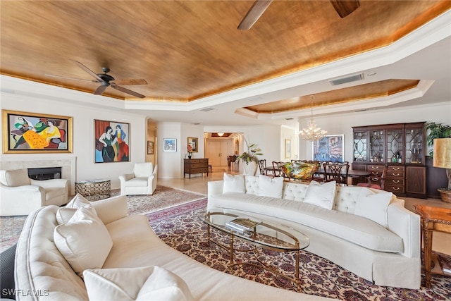 living room with ceiling fan with notable chandelier, a tray ceiling, hardwood / wood-style flooring, and ornamental molding