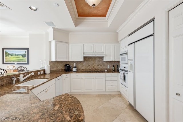 kitchen with white appliances, dark stone counters, sink, ornamental molding, and white cabinetry