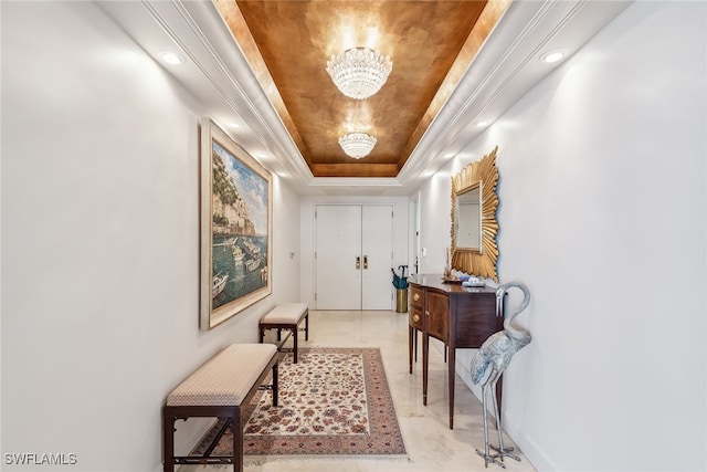 hall with a tray ceiling and a chandelier