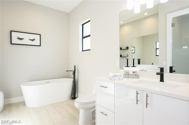 bathroom featuring vanity, a tub, hardwood / wood-style flooring, and toilet