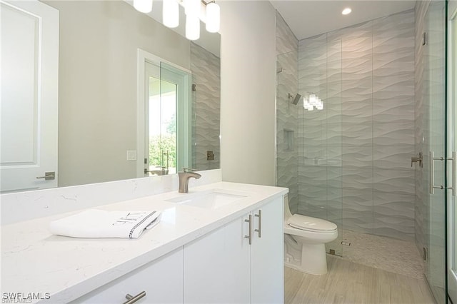 bathroom with a shower with door, vanity, hardwood / wood-style flooring, and toilet