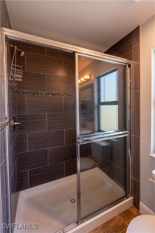 bathroom with tile patterned floors, toilet, and an enclosed shower