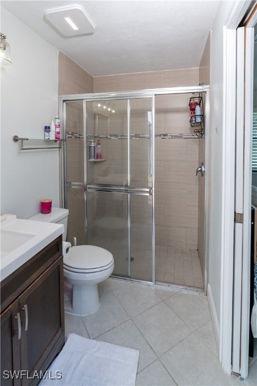 bathroom with vanity, tile patterned flooring, toilet, and an enclosed shower