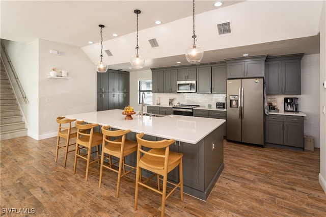 kitchen with gray cabinetry, sink, a kitchen bar, stainless steel appliances, and lofted ceiling