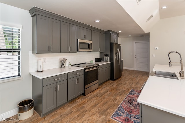 kitchen with lofted ceiling, gray cabinetry, sink, appliances with stainless steel finishes, and dark hardwood / wood-style flooring