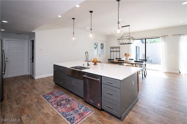 kitchen featuring dark hardwood / wood-style flooring, stainless steel appliances, sink, and an island with sink