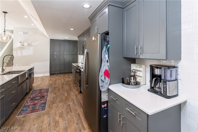 kitchen with gray cabinetry, appliances with stainless steel finishes, dark hardwood / wood-style flooring, and hanging light fixtures