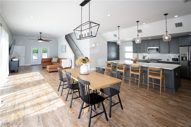 dining room with lofted ceiling, hardwood / wood-style flooring, and ceiling fan with notable chandelier