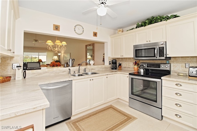 kitchen with ceiling fan with notable chandelier, pendant lighting, tasteful backsplash, sink, and stainless steel appliances