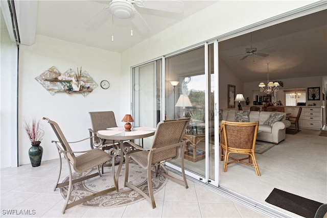 dining space featuring light tile patterned floors, ceiling fan with notable chandelier, and vaulted ceiling