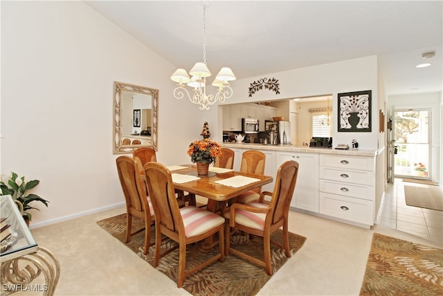 dining space with vaulted ceiling, light colored carpet, and a chandelier