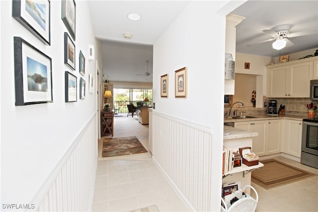 hall featuring light tile patterned flooring and sink