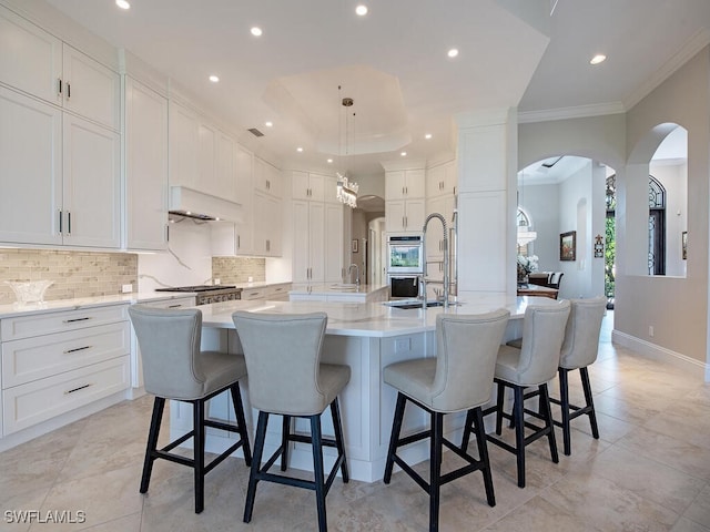 kitchen featuring a spacious island, a kitchen breakfast bar, white cabinets, and backsplash