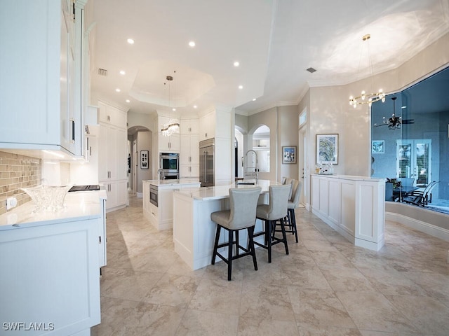 kitchen featuring white cabinetry, stainless steel appliances, hanging light fixtures, and a large island with sink