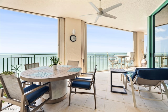 sunroom / solarium with a water view, a healthy amount of sunlight, and ceiling fan