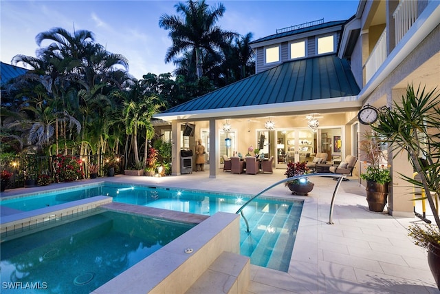 pool at dusk with outdoor lounge area and an in ground hot tub