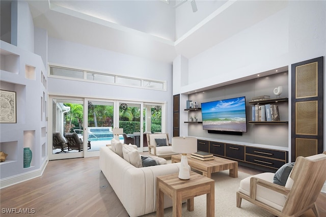 living room featuring a towering ceiling and light hardwood / wood-style floors