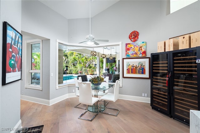 dining room featuring wine cooler, ceiling fan, plenty of natural light, and a towering ceiling