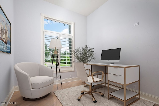 home office featuring a healthy amount of sunlight, lofted ceiling, and light hardwood / wood-style floors