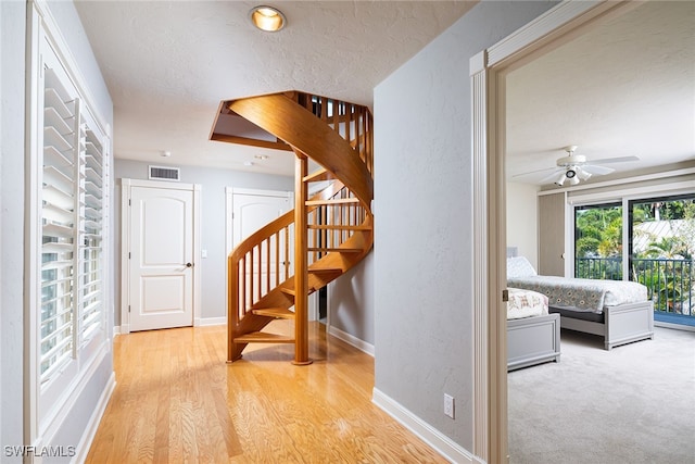 corridor with light carpet and a textured ceiling