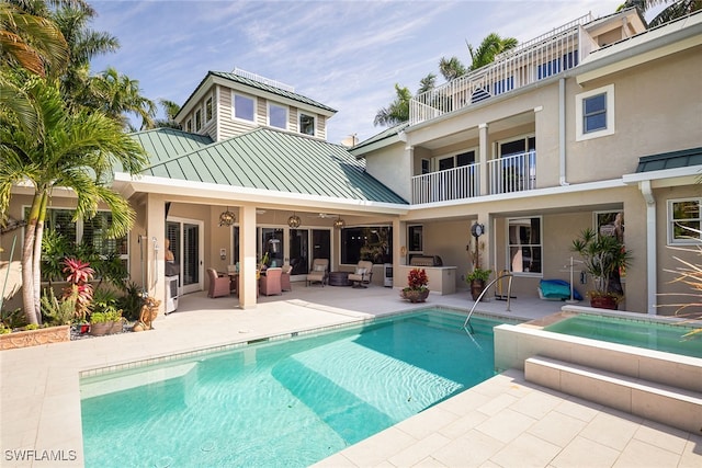 rear view of house with a patio, a balcony, area for grilling, and a pool with hot tub