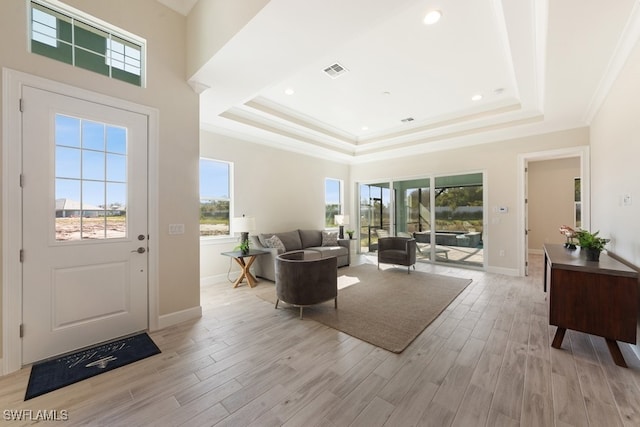 living room with light hardwood / wood-style floors, a raised ceiling, and crown molding