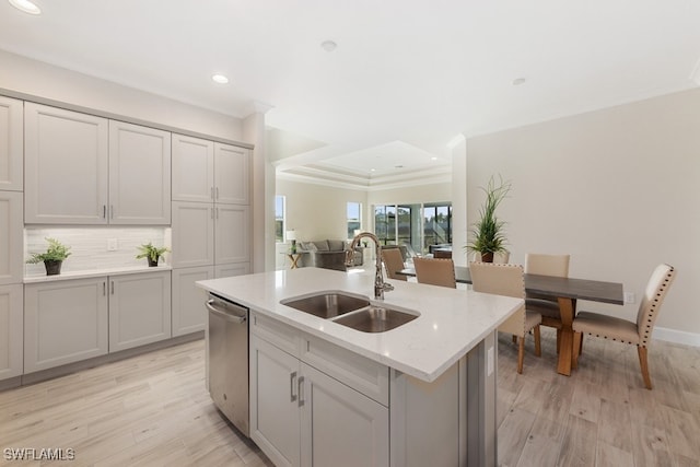 kitchen featuring light hardwood / wood-style flooring, sink, stainless steel dishwasher, and a center island with sink