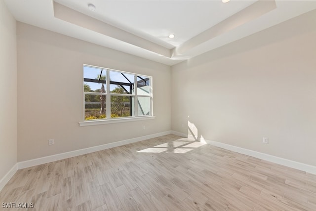 unfurnished room featuring a tray ceiling and light hardwood / wood-style floors