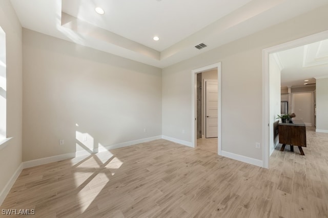 empty room with a raised ceiling and light wood-type flooring