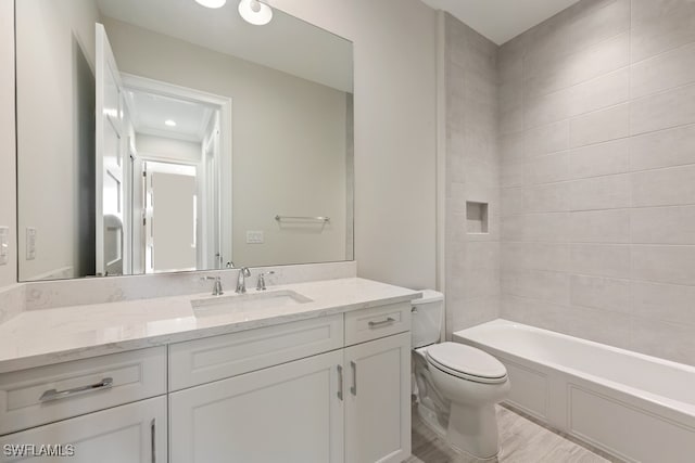 full bathroom with vanity, tiled shower / bath combo, toilet, and wood-type flooring