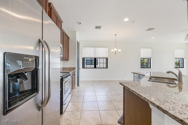 kitchen with pendant lighting, an inviting chandelier, sink, light stone countertops, and appliances with stainless steel finishes