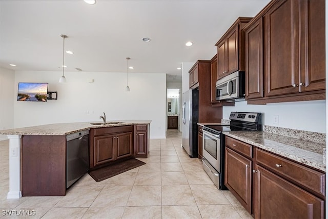 kitchen with a center island with sink, sink, light stone countertops, appliances with stainless steel finishes, and decorative light fixtures