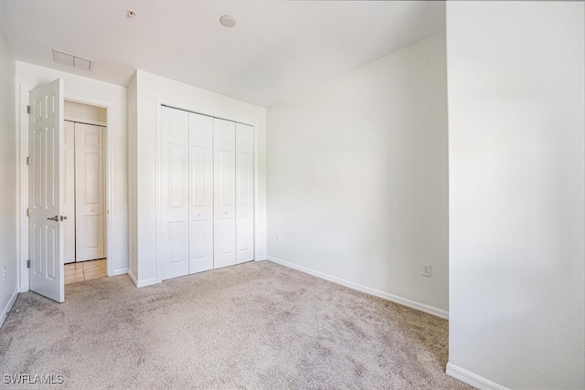 unfurnished bedroom featuring light colored carpet and a closet