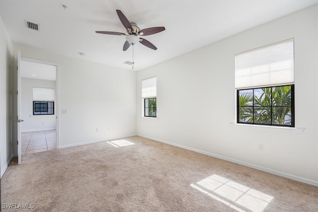 carpeted spare room featuring ceiling fan and a healthy amount of sunlight