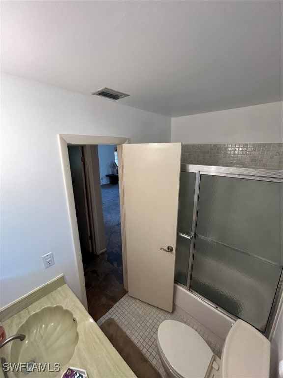 bathroom featuring tile patterned flooring, vanity, toilet, and a shower with door