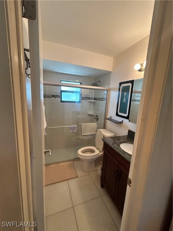 bathroom with tile patterned flooring, an enclosed shower, vanity, and toilet