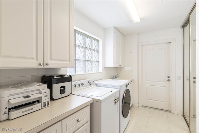 laundry area featuring cabinets, light tile patterned floors, and washer and clothes dryer