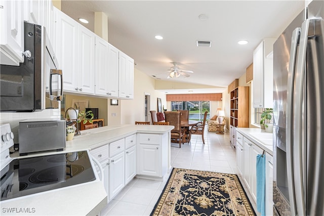 kitchen featuring white cabinets, vaulted ceiling, light tile patterned floors, kitchen peninsula, and stainless steel appliances