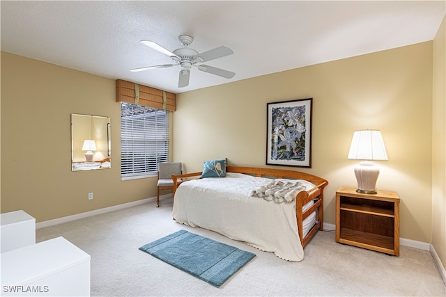 bedroom with ceiling fan, light colored carpet, and a textured ceiling