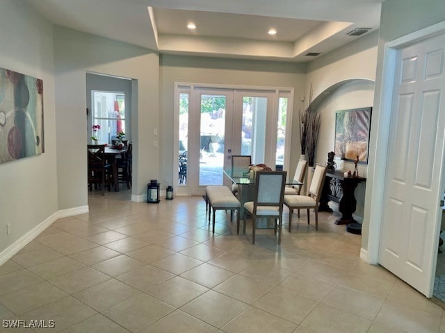 interior space with french doors, light tile patterned flooring, and a tray ceiling